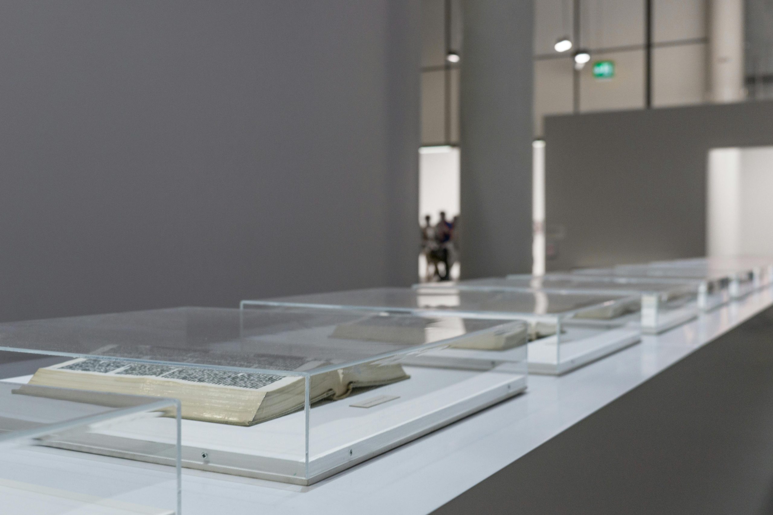 Modern art museum exhibit featuring open books in glass cases, highlighting contemporary interior design.